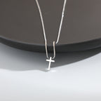 Silver cross necklace on a dark surface