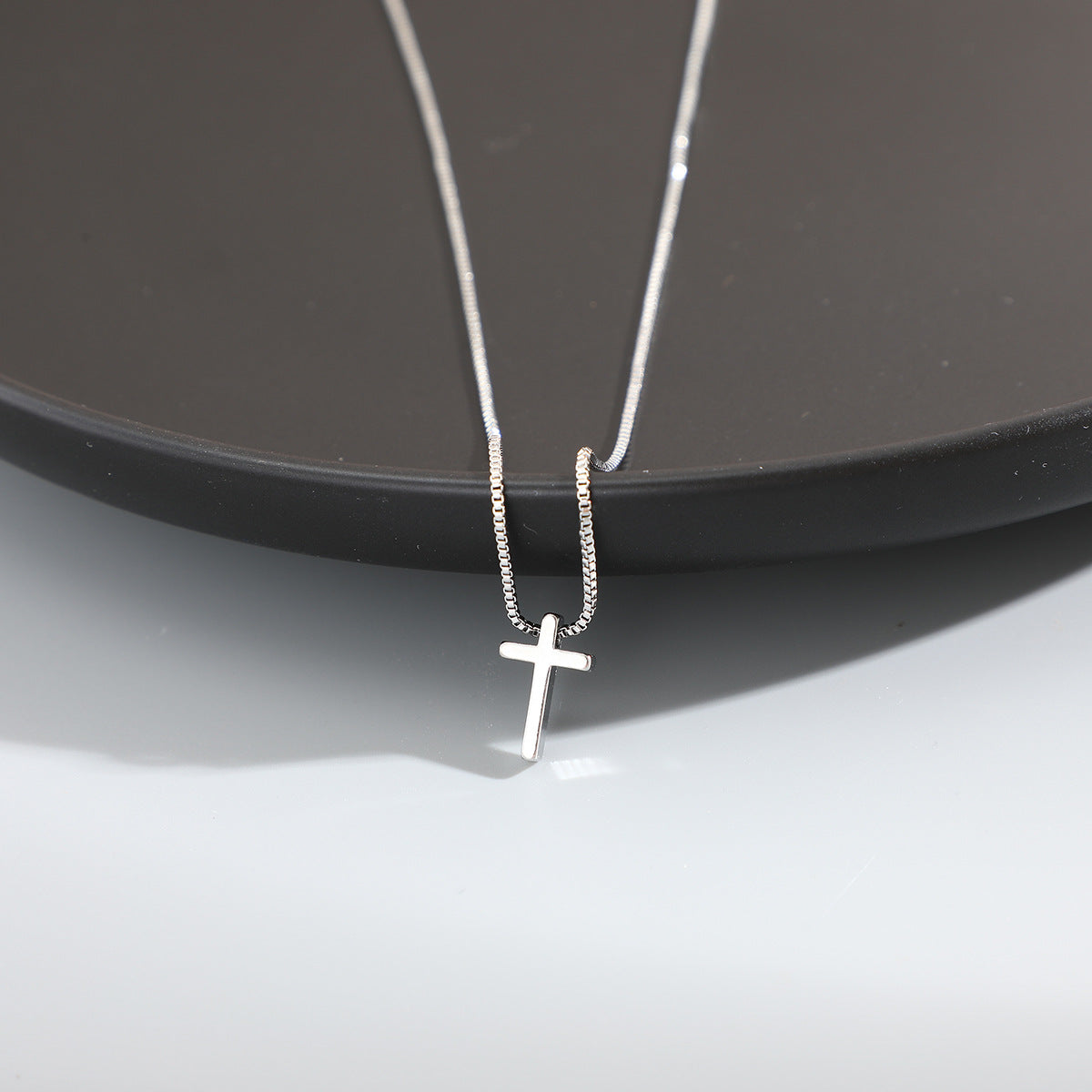 Silver cross necklace on a dark surface
