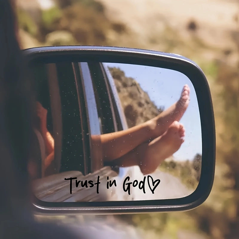 Person's feet with 'Trust in God' text reflected in a car mirror with a scenic background.
