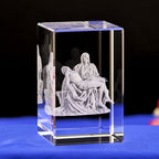 Crystal block with a religious sculpture of a woman holding a child on a blue surface.