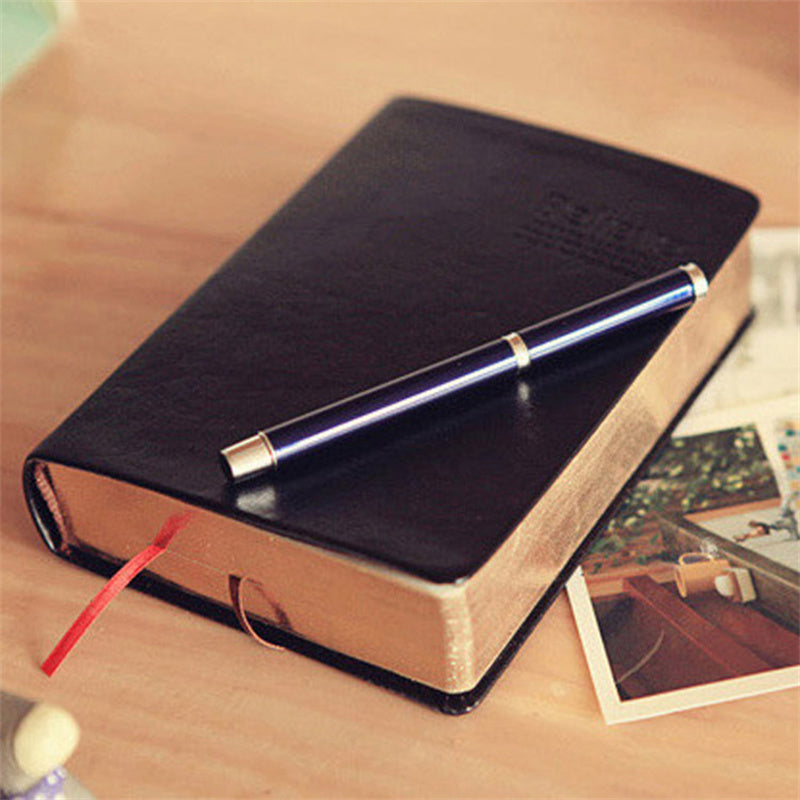 Black leather notebook with a pen on a wooden surface
