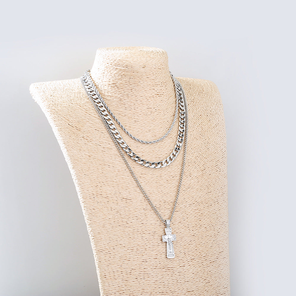 Silver chain necklace with a cross pendant on a mannequin bust against a light gray background