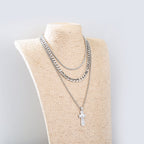 Silver chain necklace with a cross pendant on a mannequin bust against a light gray background